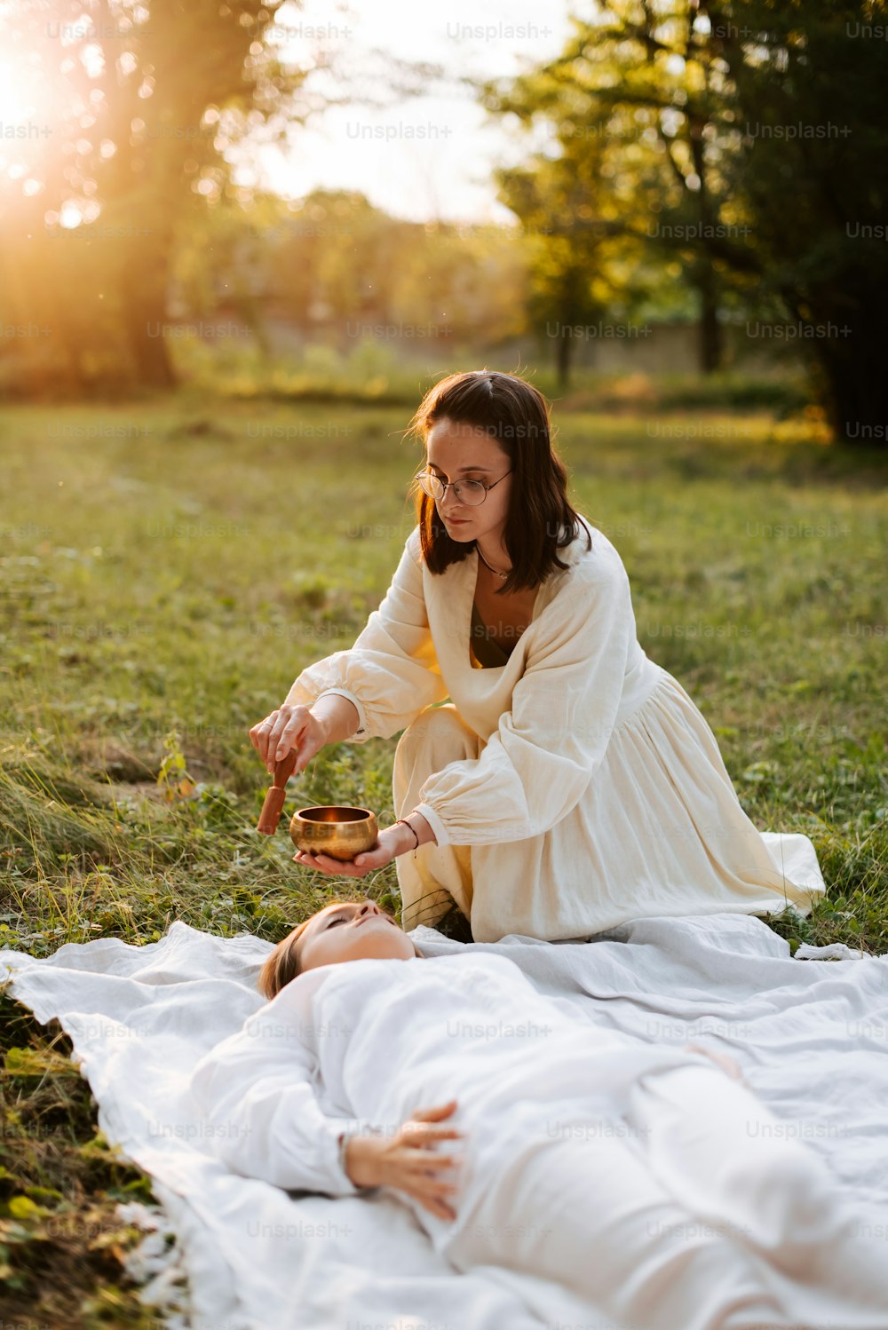 a woman in a white dress sitting on a blanket