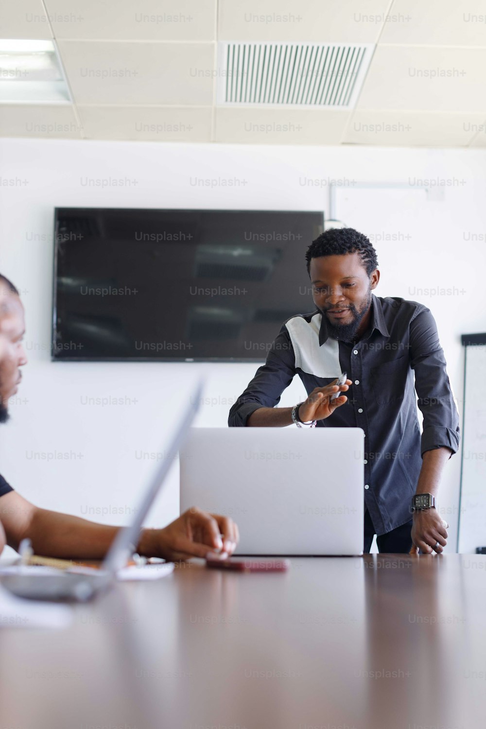 two men sitting at a table in front of a laptop