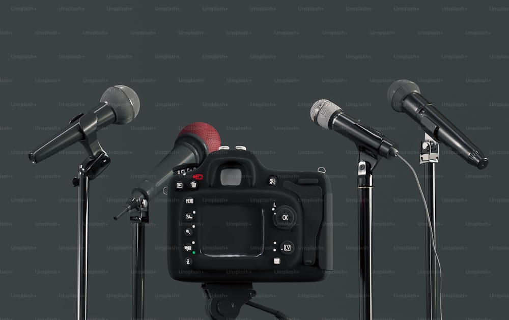 três microfones e uma câmera na frente de um fundo preto