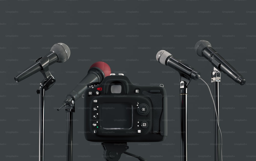 three microphones and a camera in front of a black background