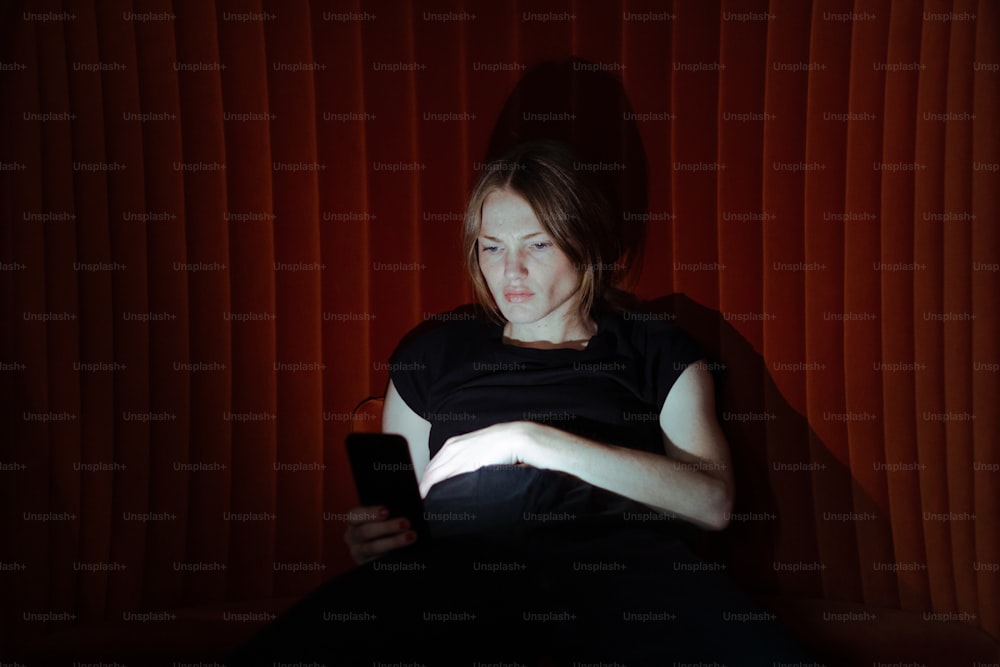 a woman sitting on a couch holding a cell phone
