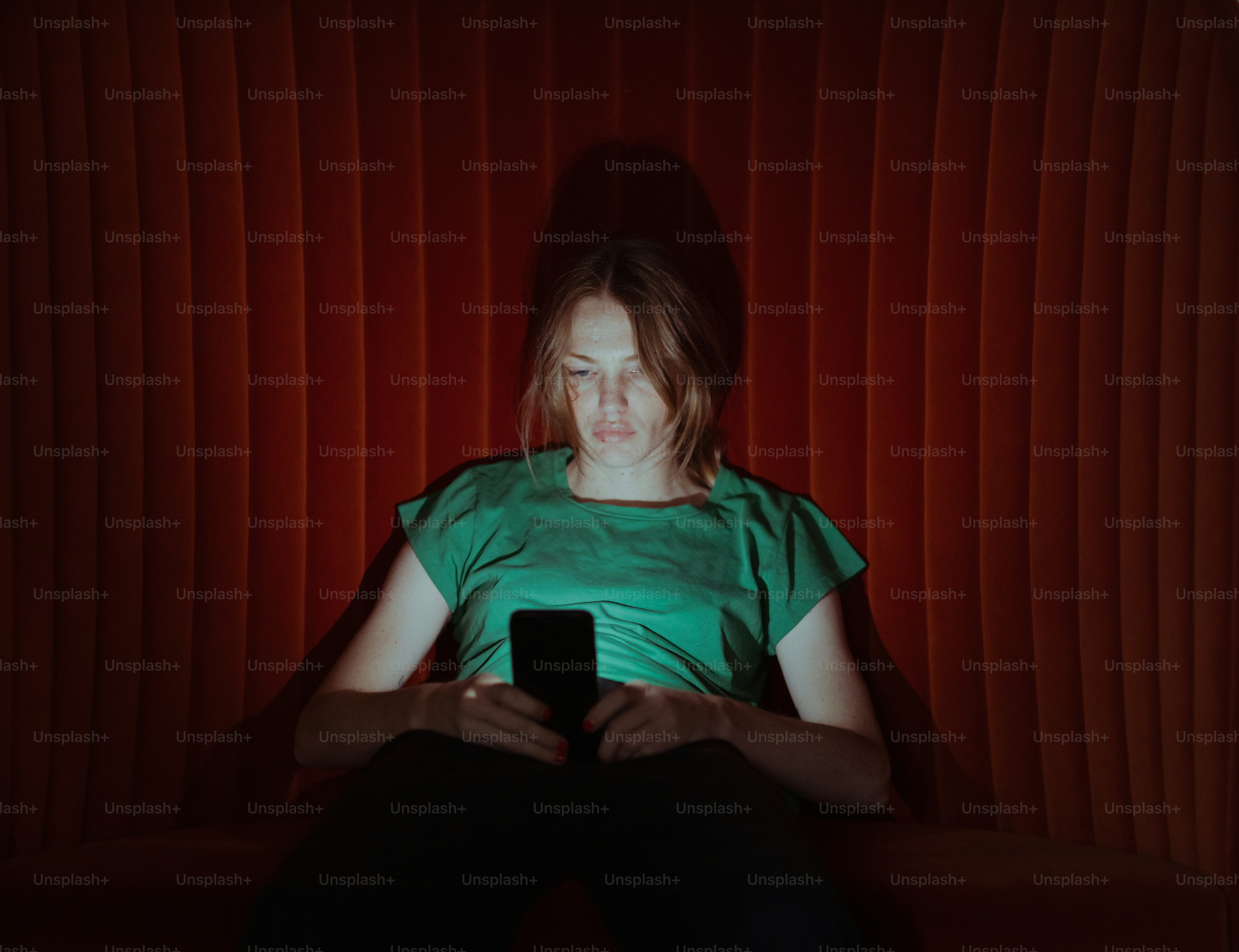 Une femme assise sur un canapé regardant un téléphone portable