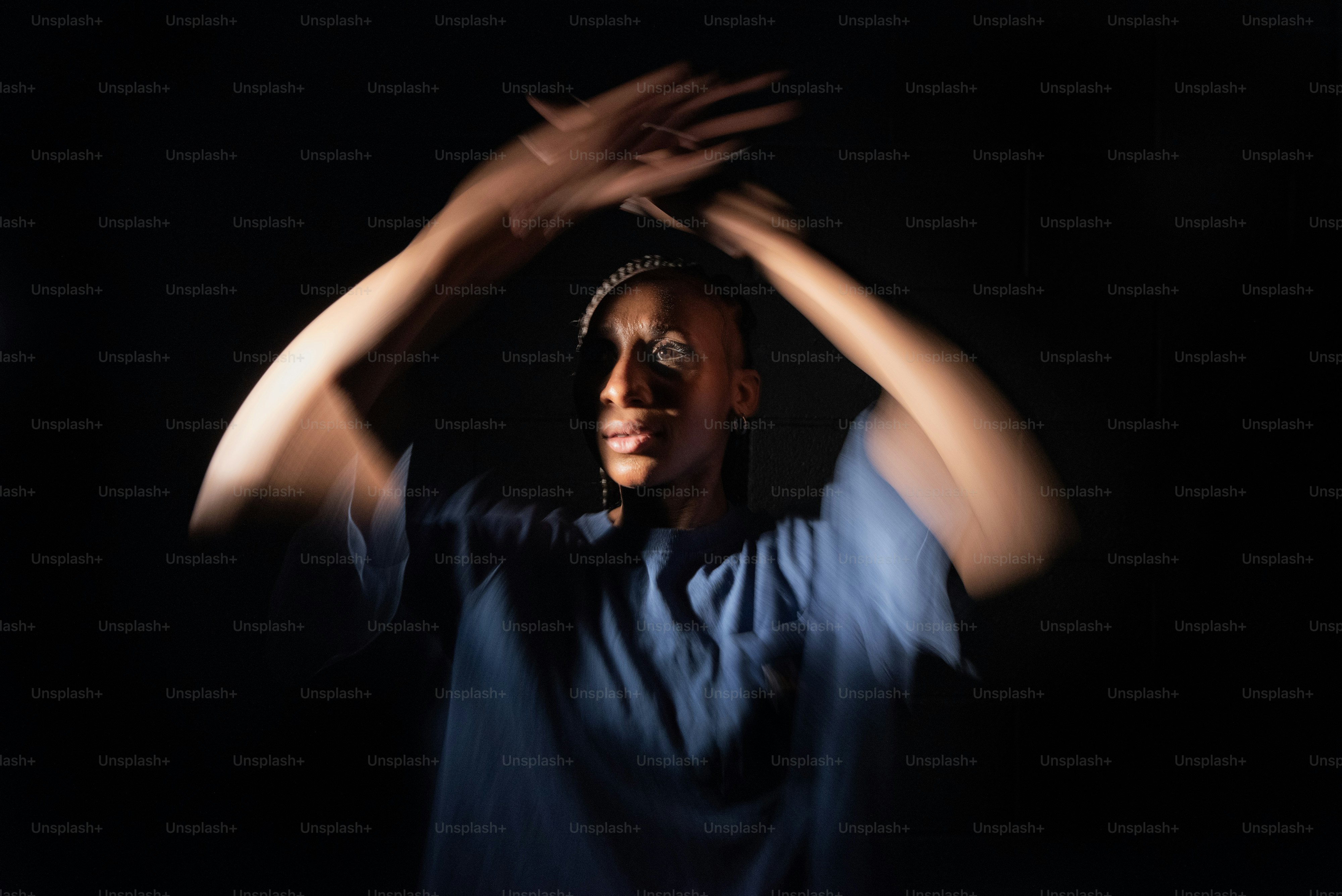 a woman in a blue shirt is holding her hands up