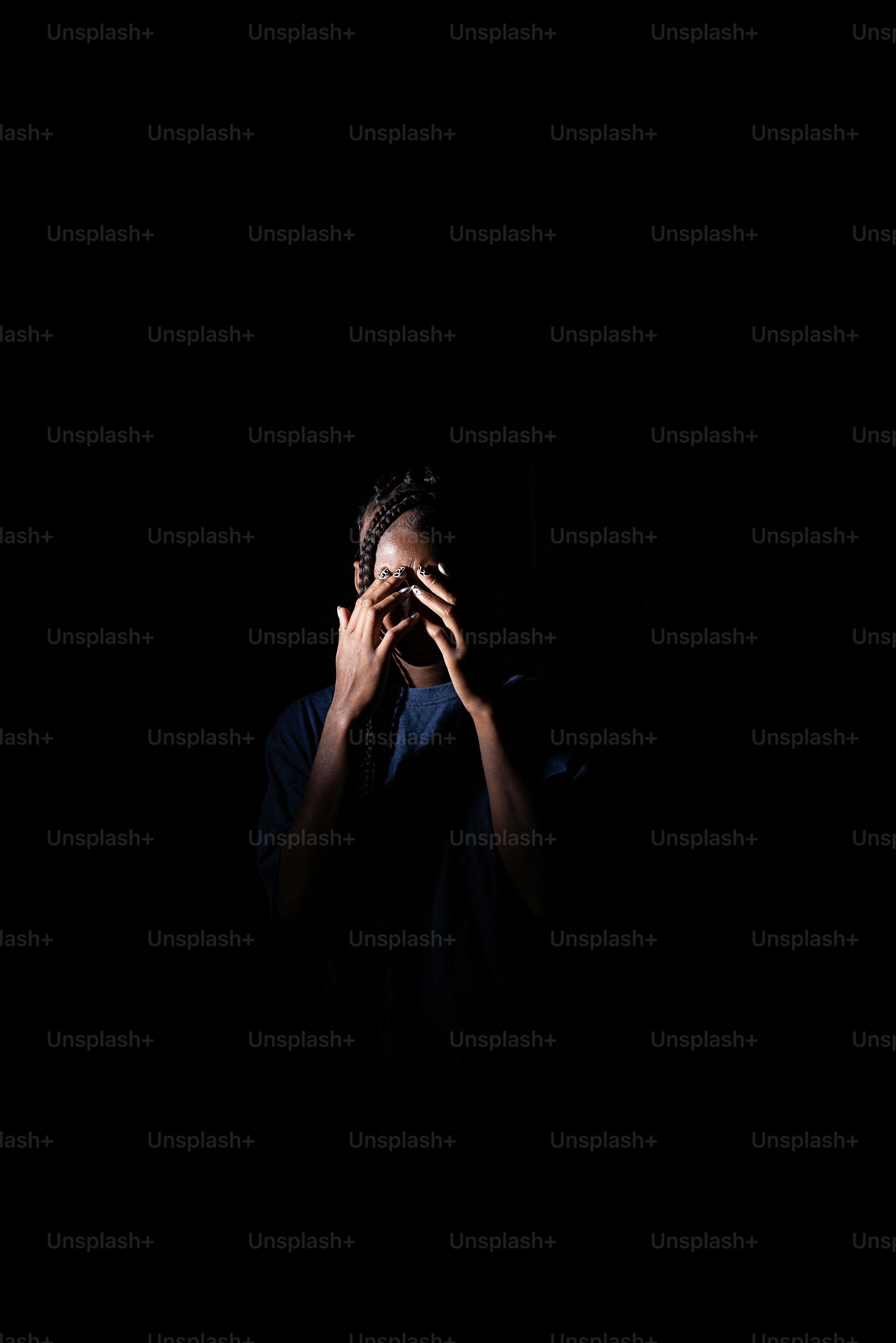 a person standing in the dark holding their hands to their face