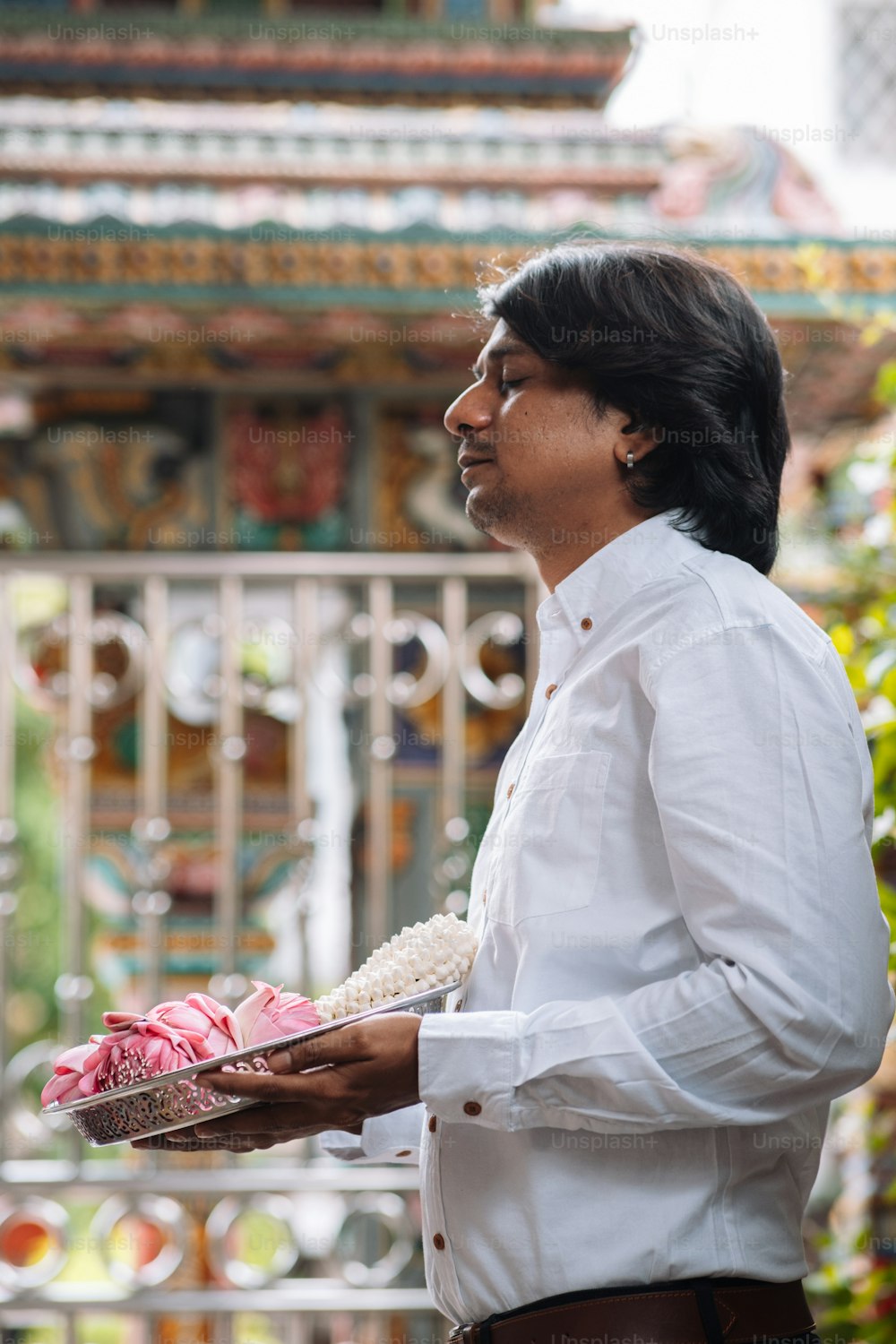 ein Mann in einem weißen Hemd, der einen Blumenkorb hält