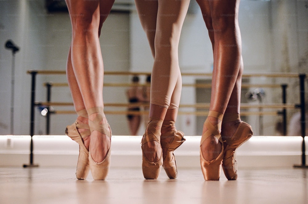 three ballerinas are standing in a ballet studio