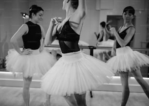 a black and white photo of three ballerinas