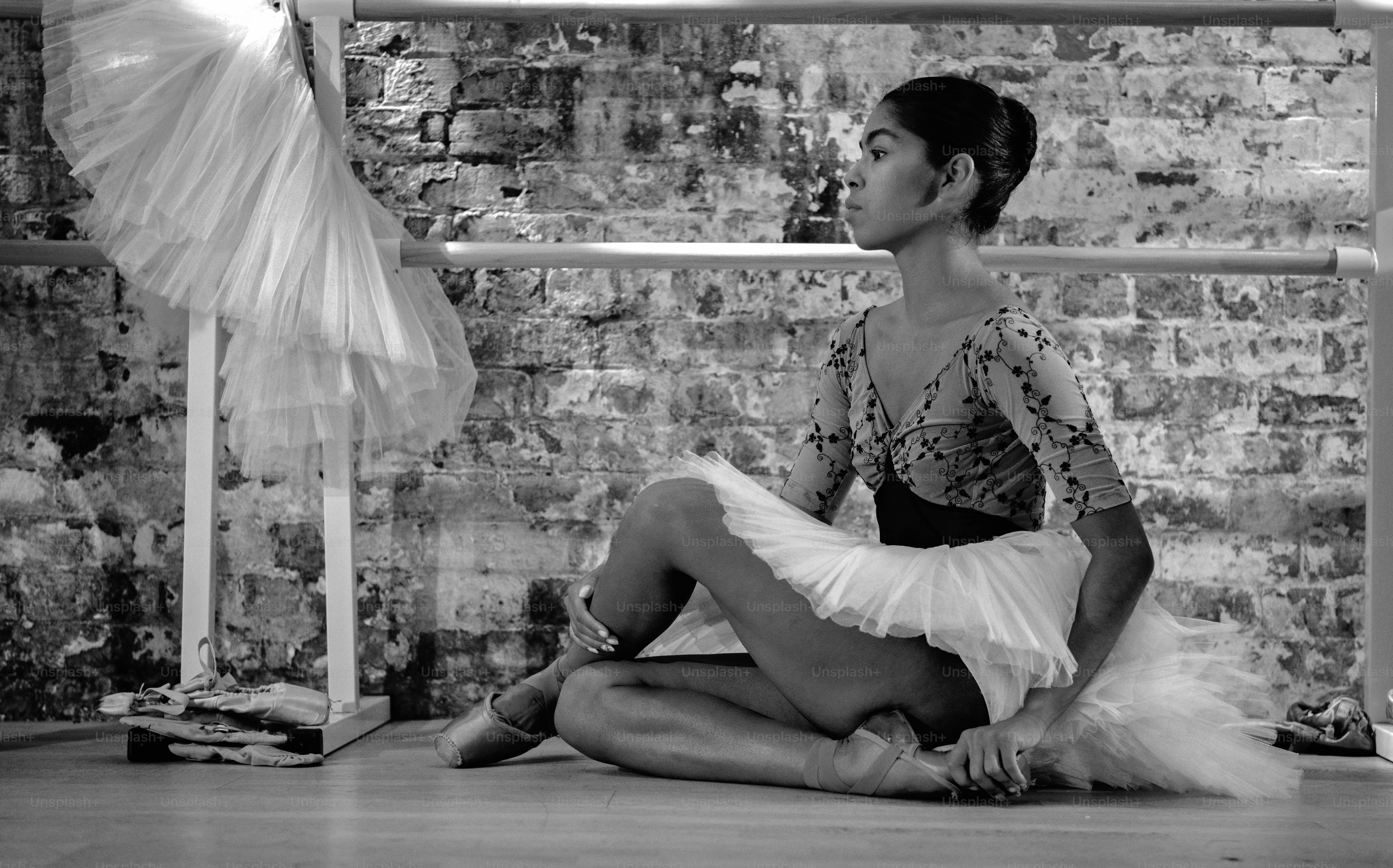 a woman sitting on the floor in front of a brick wall