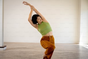a woman in a green shirt is doing a yoga pose