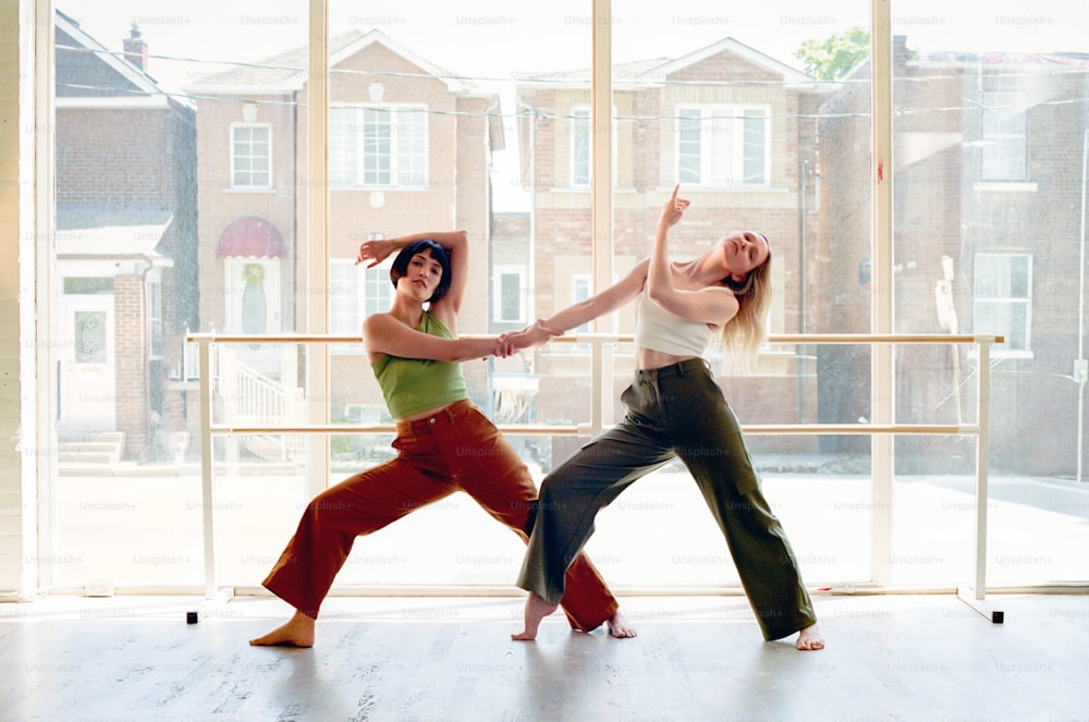two women in a dance pose in front of a window