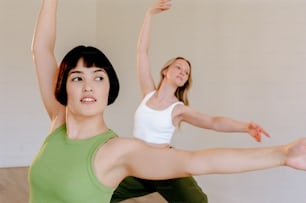 two women in a dance pose with their arms in the air
