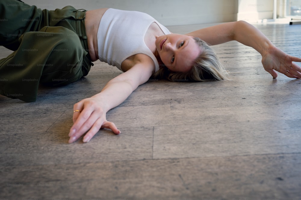 a woman laying on the floor in a white top