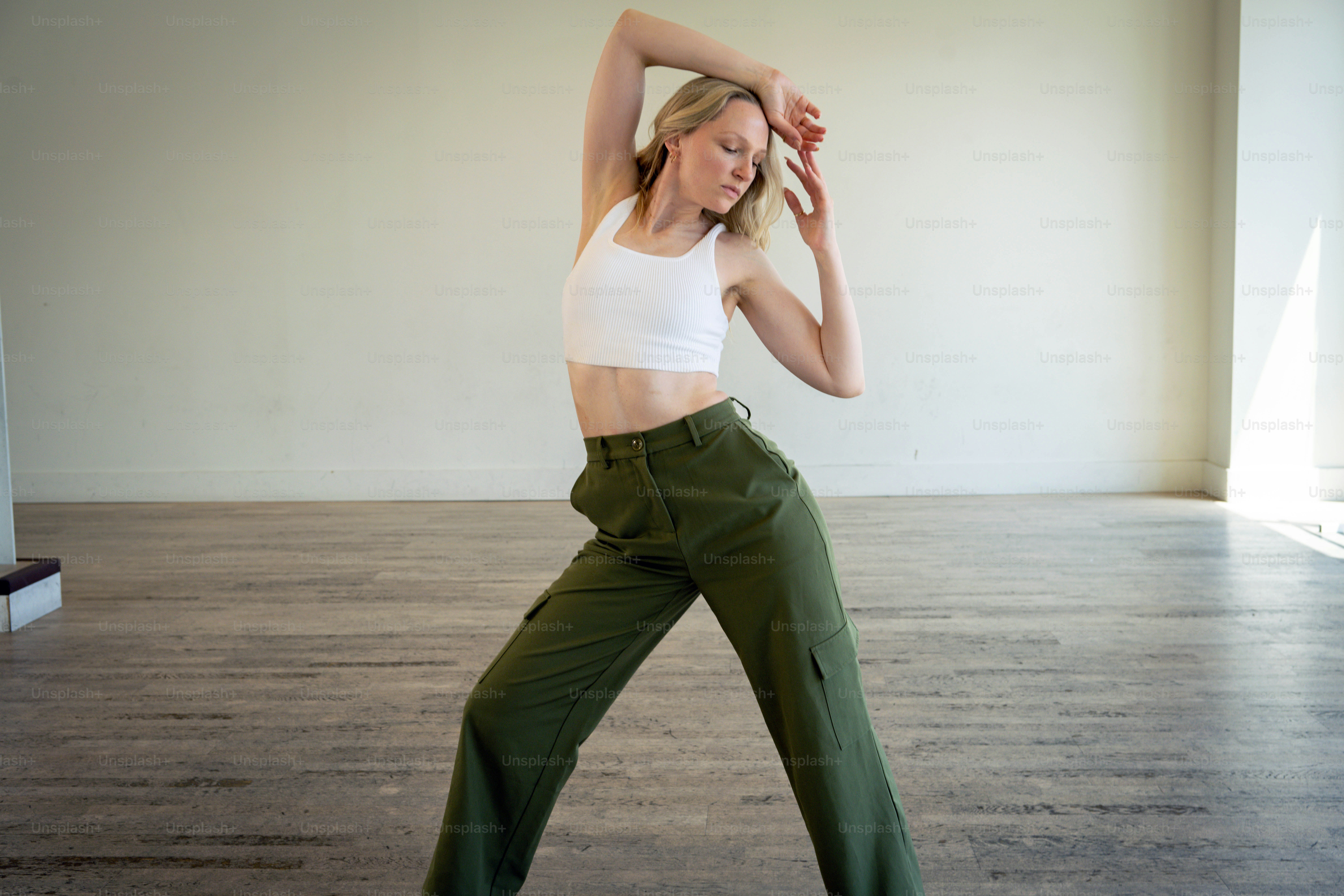 a woman in a white top and green pants