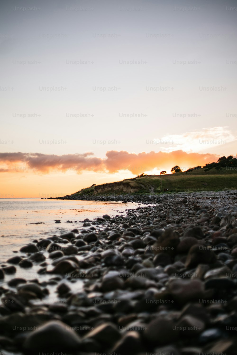 the sun is setting over a rocky beach