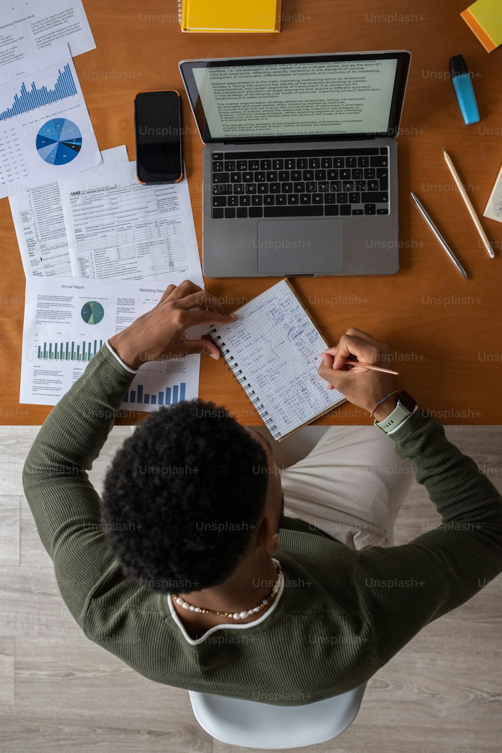 a person sitting at a desk with papers and a laptop