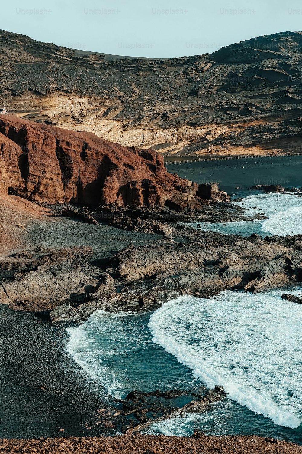 uma praia rochosa com um corpo de água ao lado
