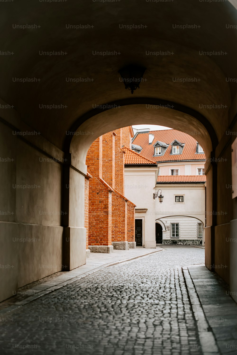 a cobblestone street with an archway leading to a building