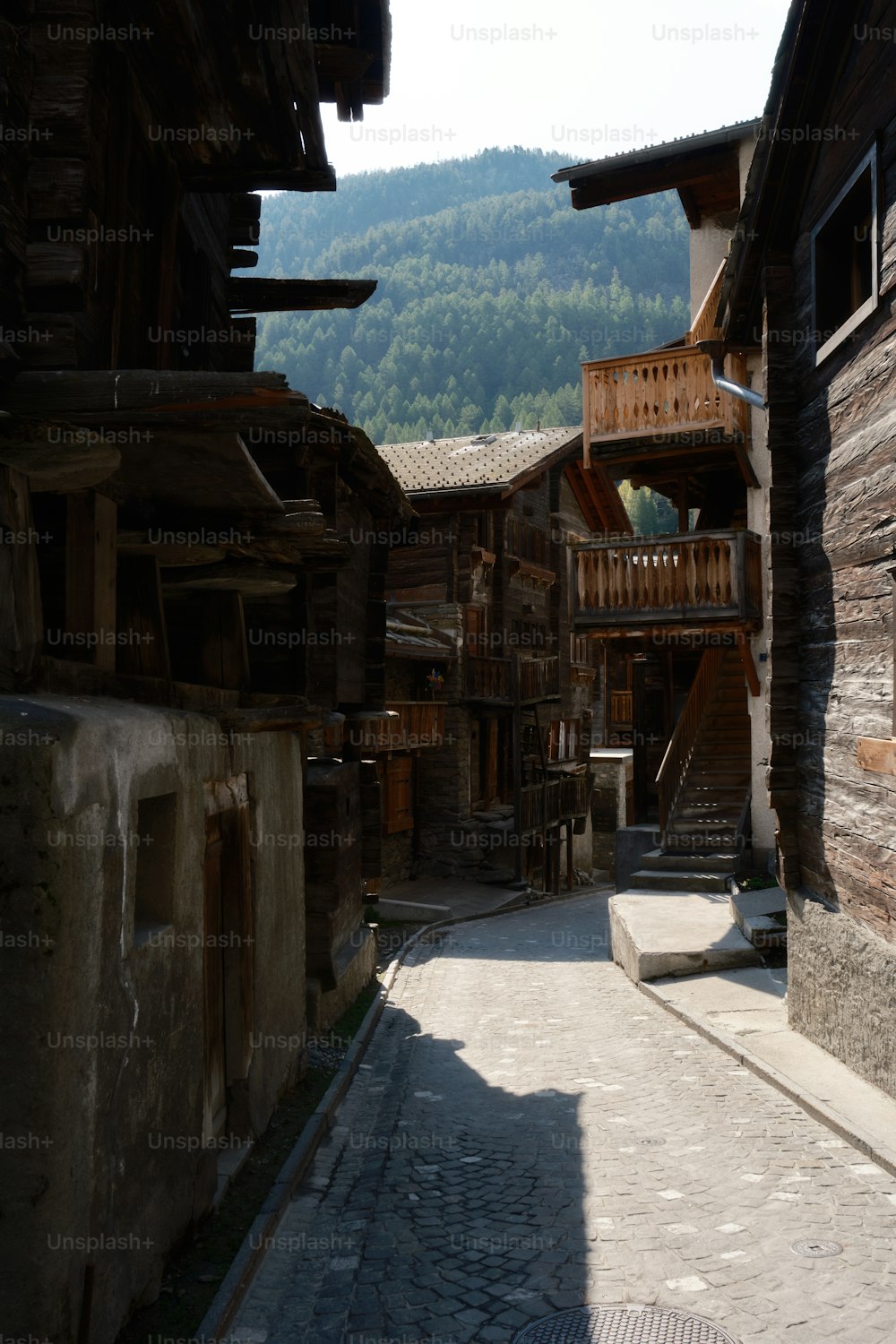 a cobblestone street with a wooden building in the background