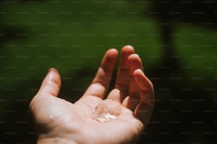 uma mão segurando uma gota de água na palma da mão