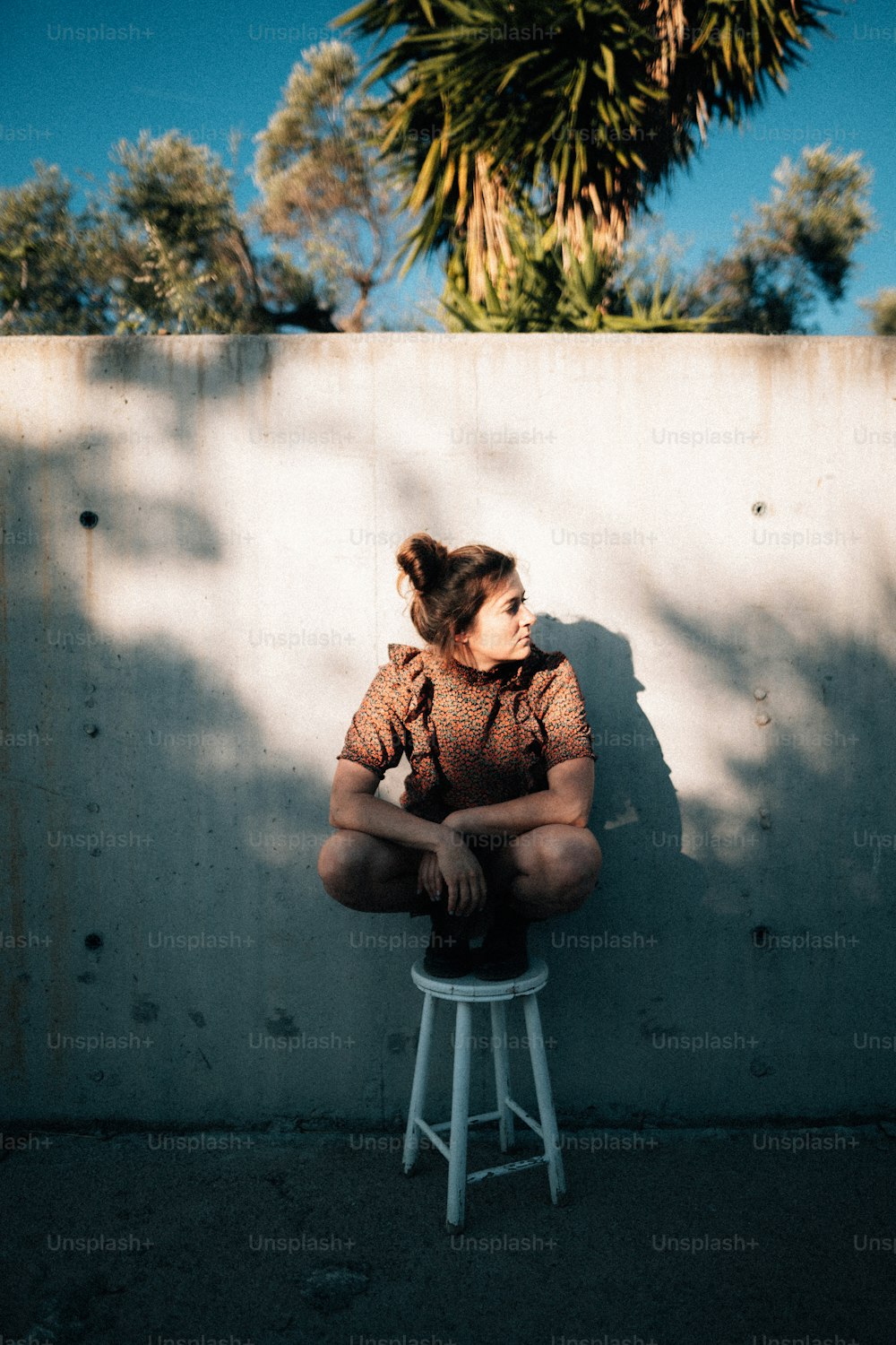 a woman sitting on a stool in front of a wall