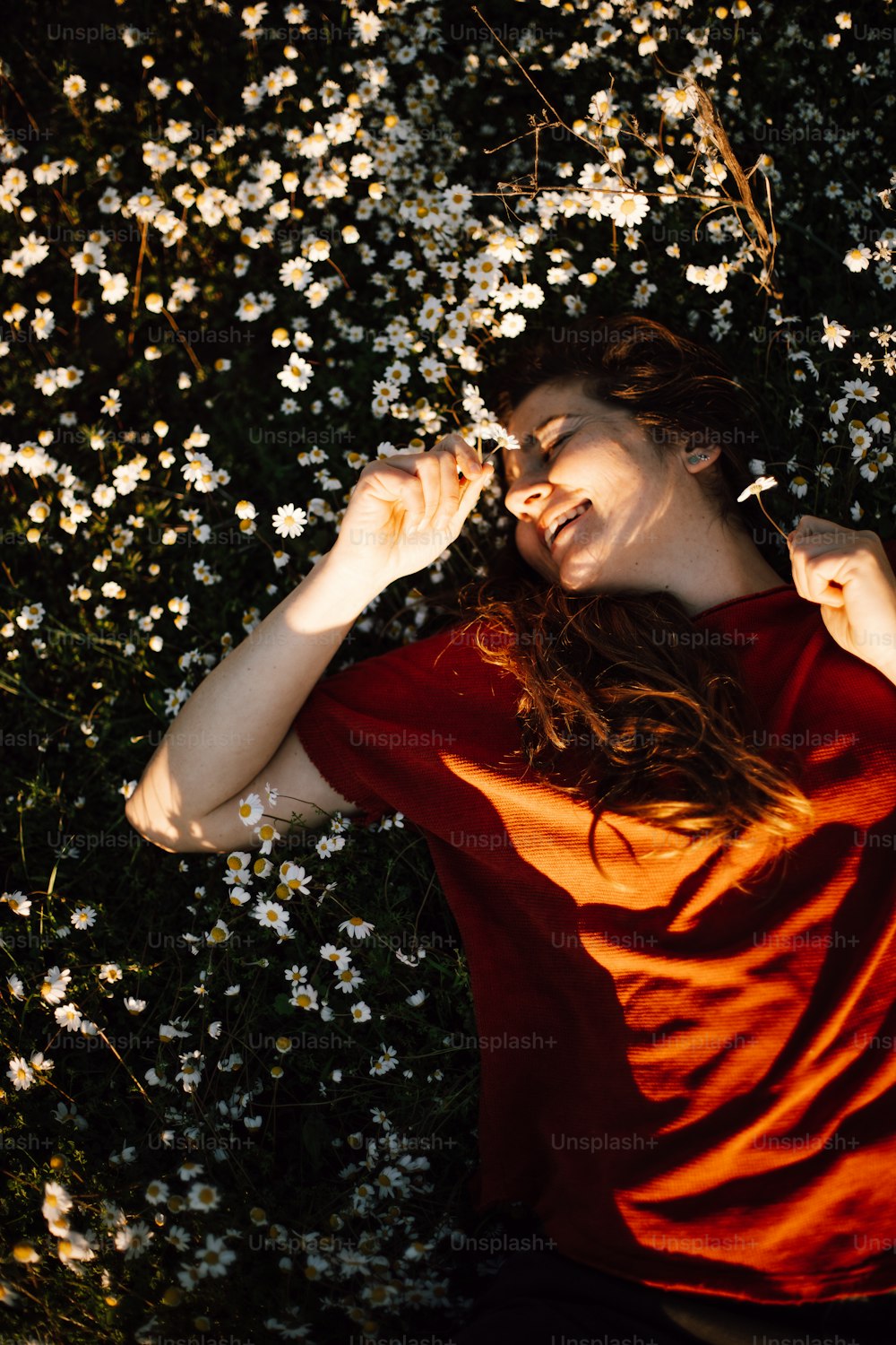 a woman in a red shirt laying in a field of flowers