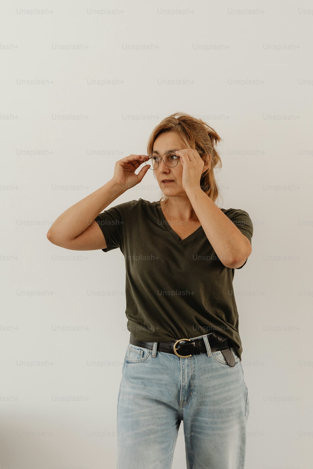 a woman in a green shirt is holding her glasses