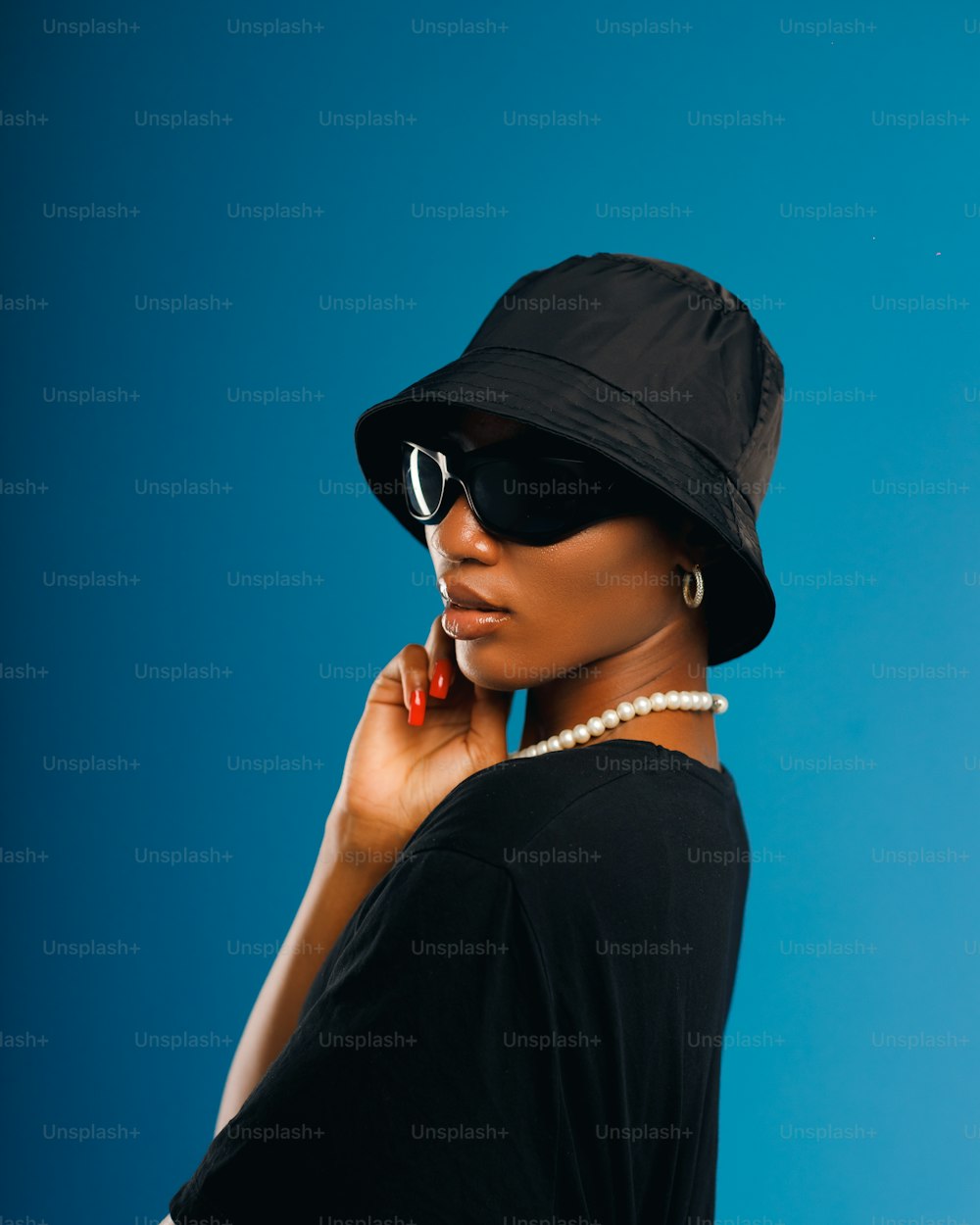 a woman wearing a black hat and sunglasses talking on a cell phone