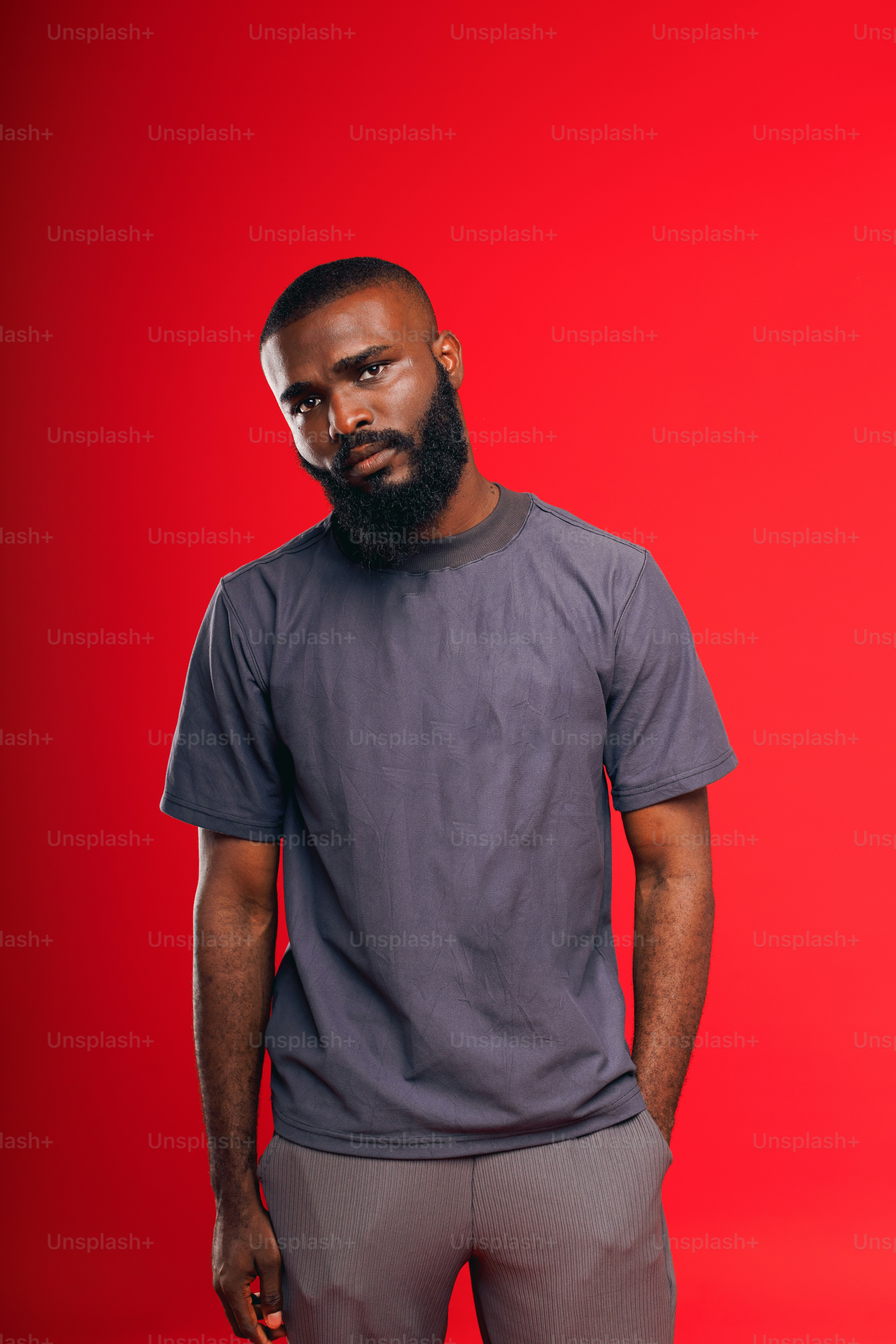 a man with a beard standing in front of a red background