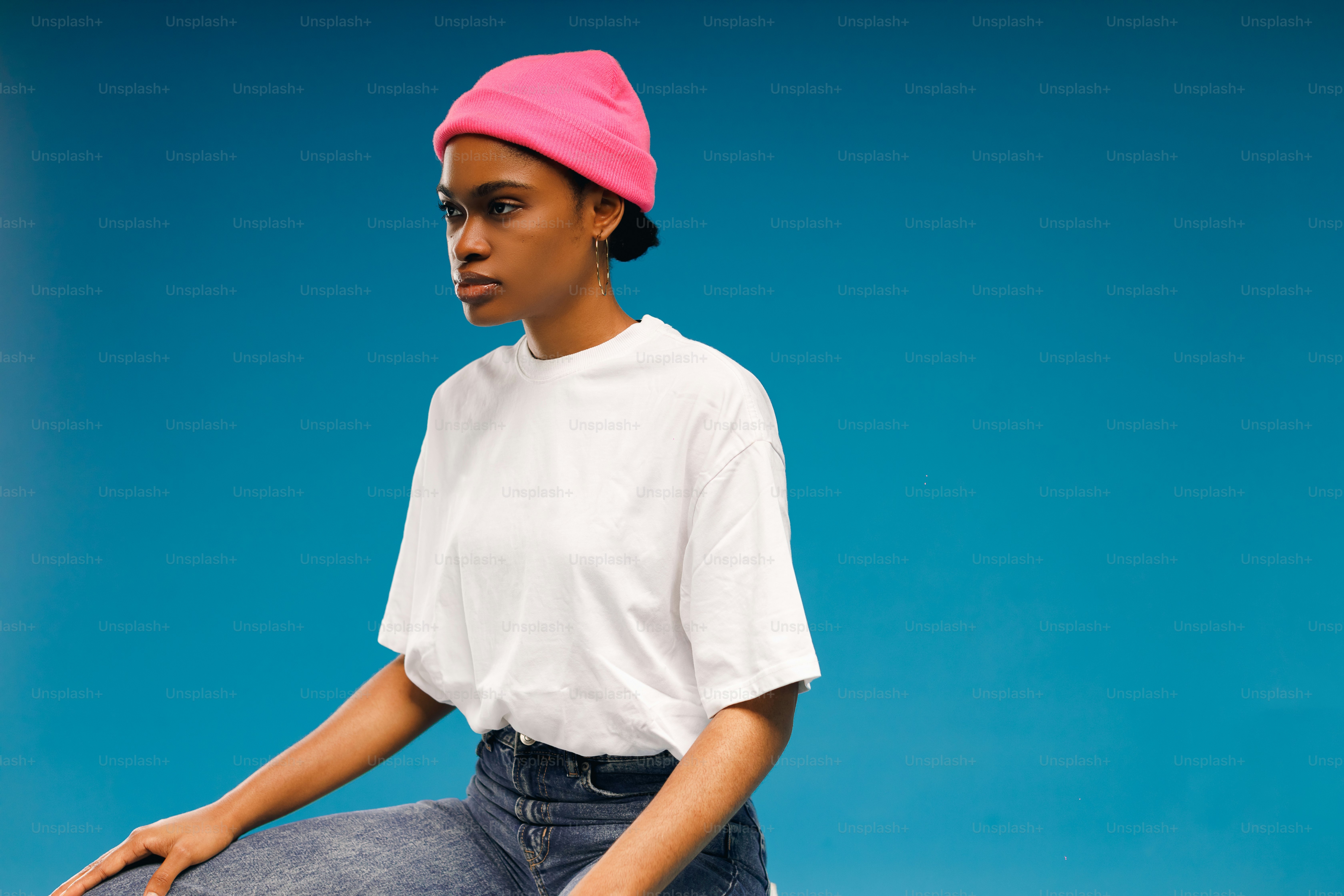 분홍색 모자를 쓴 여자가 스케이트보드에 앉아 있다