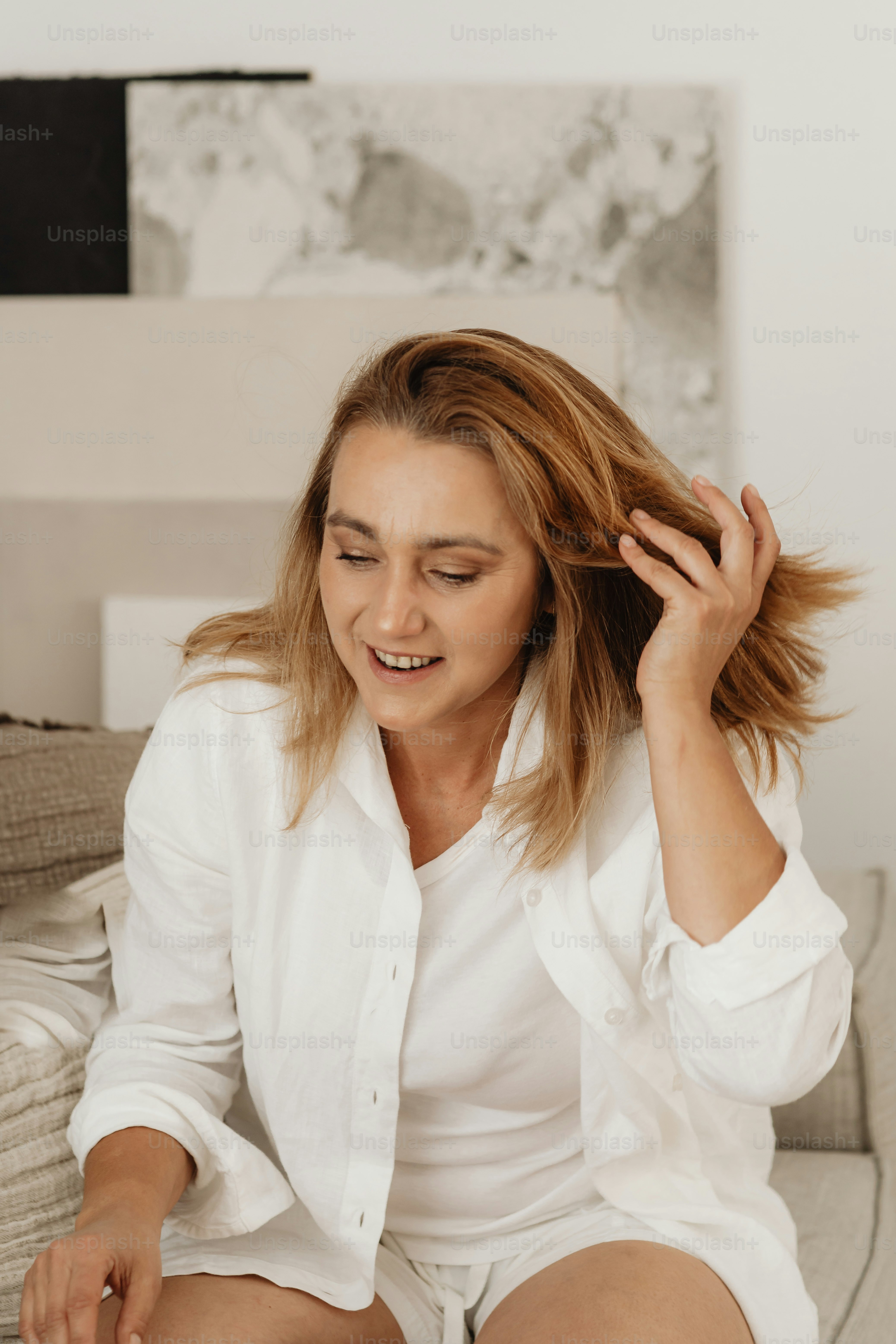 Una mujer sentada en un sofá sosteniendo su cabello