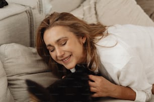 a woman laying on a couch petting a cat