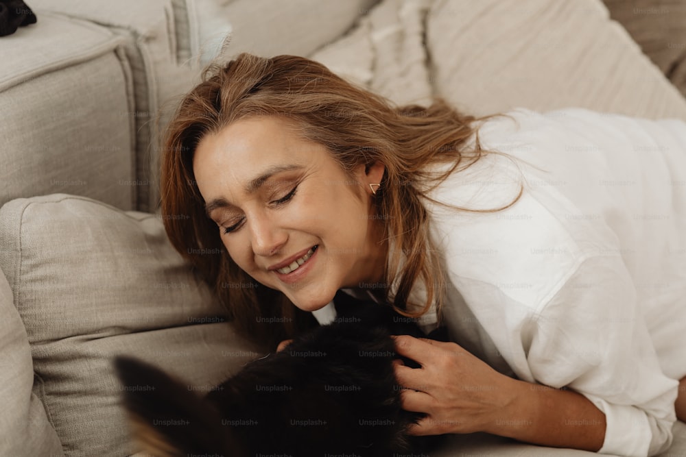 a woman laying on a couch petting a cat