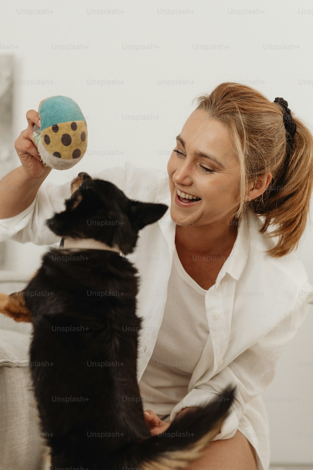 a woman is playing with a dog and a ball
