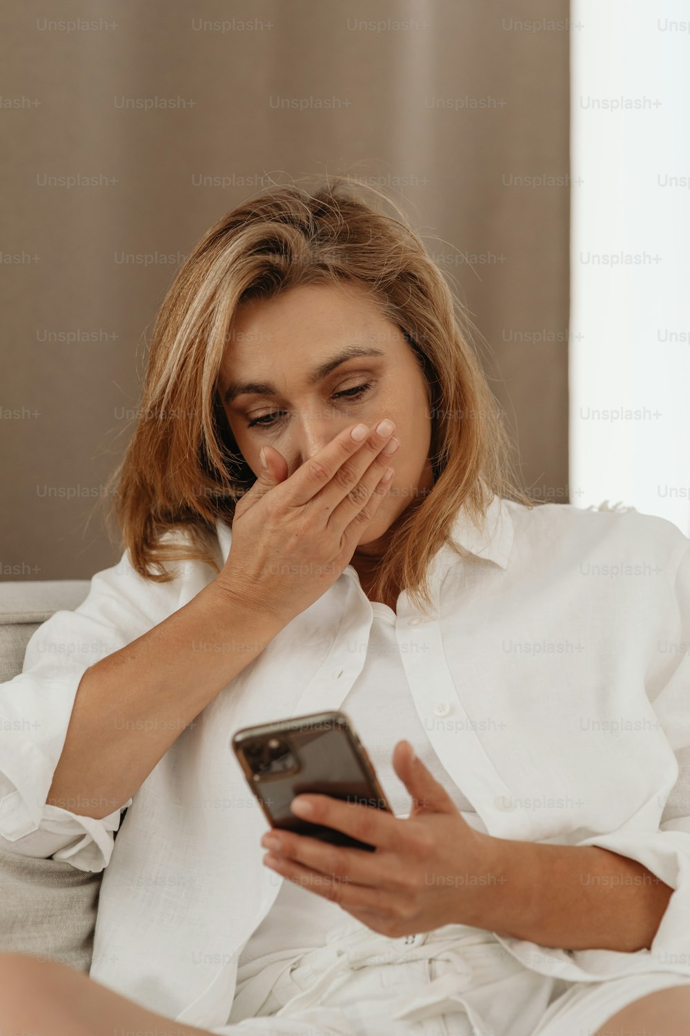 a woman sitting on a couch looking at a cell phone