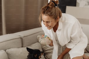 a woman playing with a dog on a couch