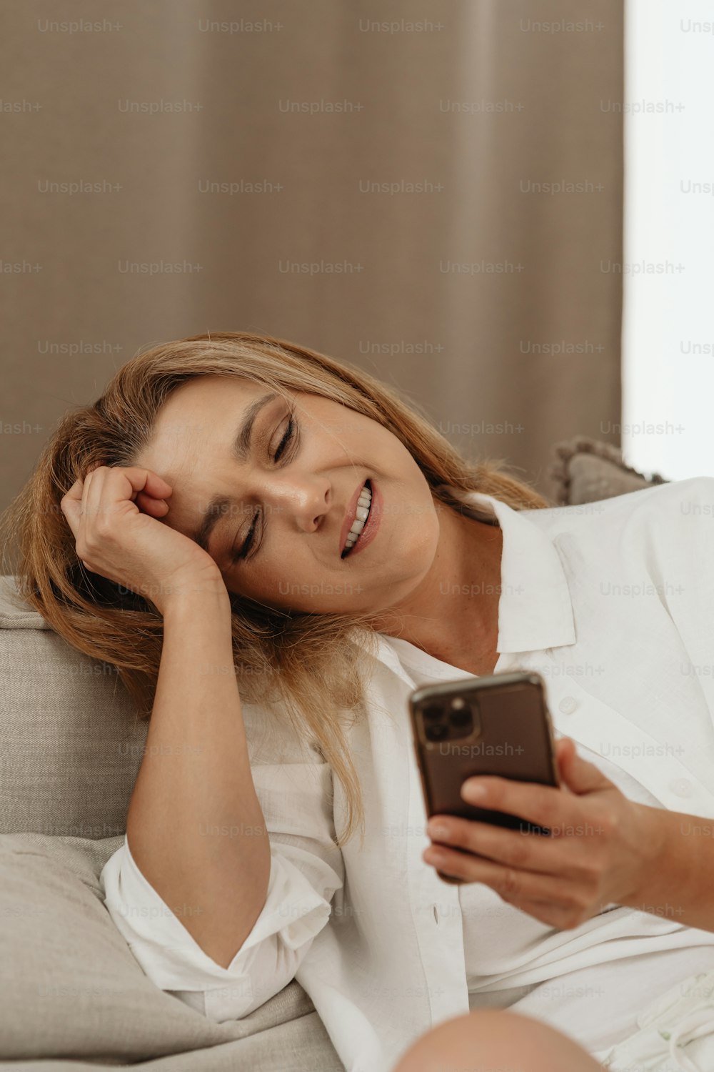 uma mulher sentada em um sofá olhando para seu celular