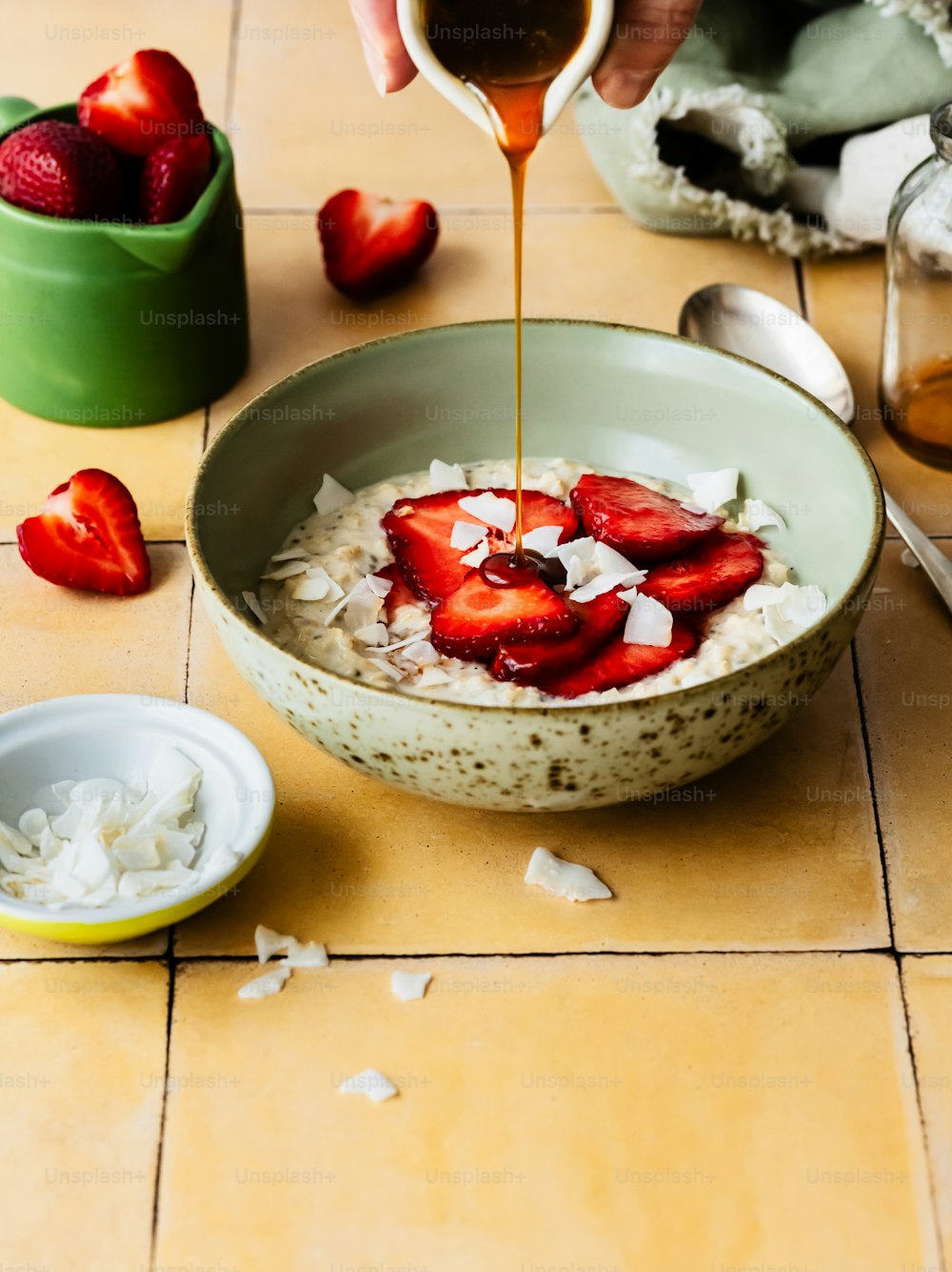 a bowl of oatmeal with strawberries being drizzled with