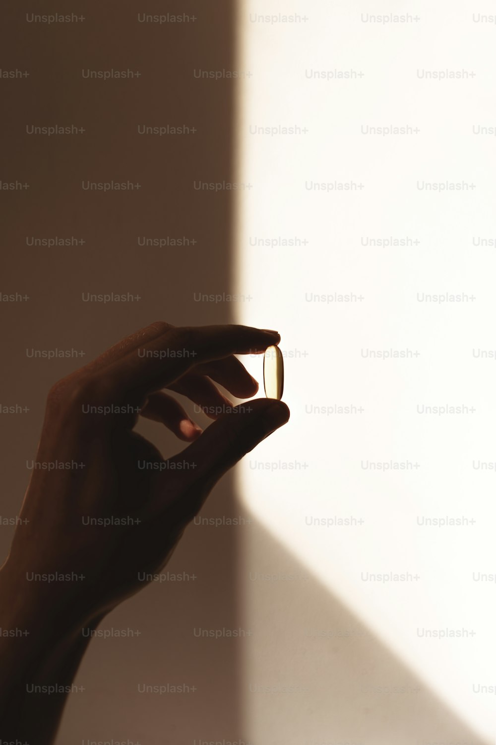 a person's hand holding a ring in front of a white wall