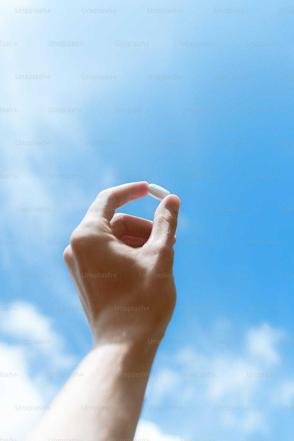 a hand reaching up into a blue sky