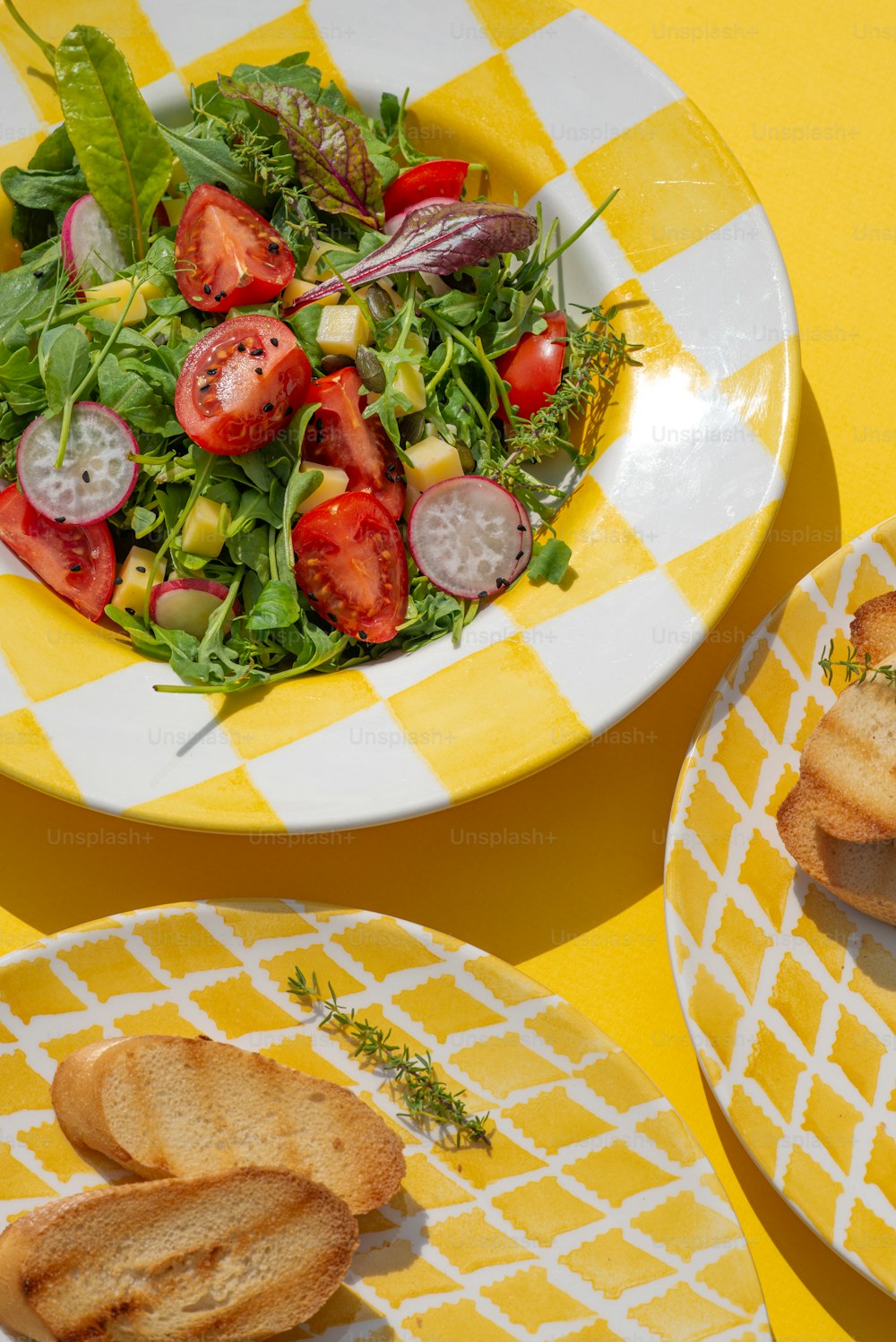 uma mesa quadriculada amarela e branca com pratos de comida