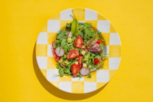 a yellow and white checkered plate with a salad on it