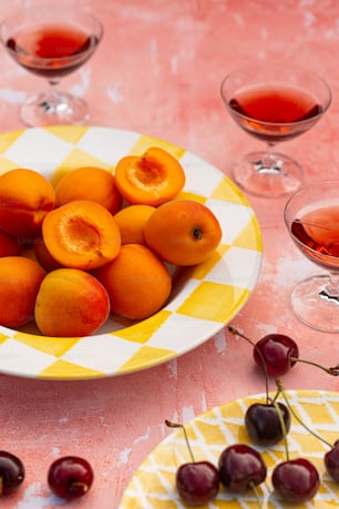 a bowl of cherries on a table with glasses of wine