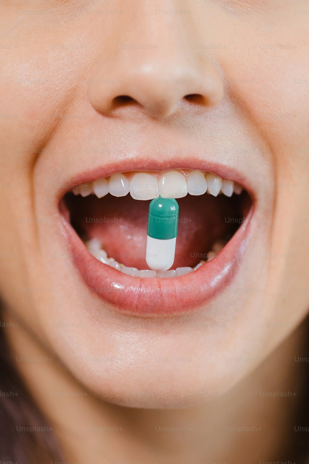 Una mujer con una píldora verde y blanca en la boca