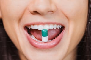 Une femme avec une pilule verte et blanche dans la bouche