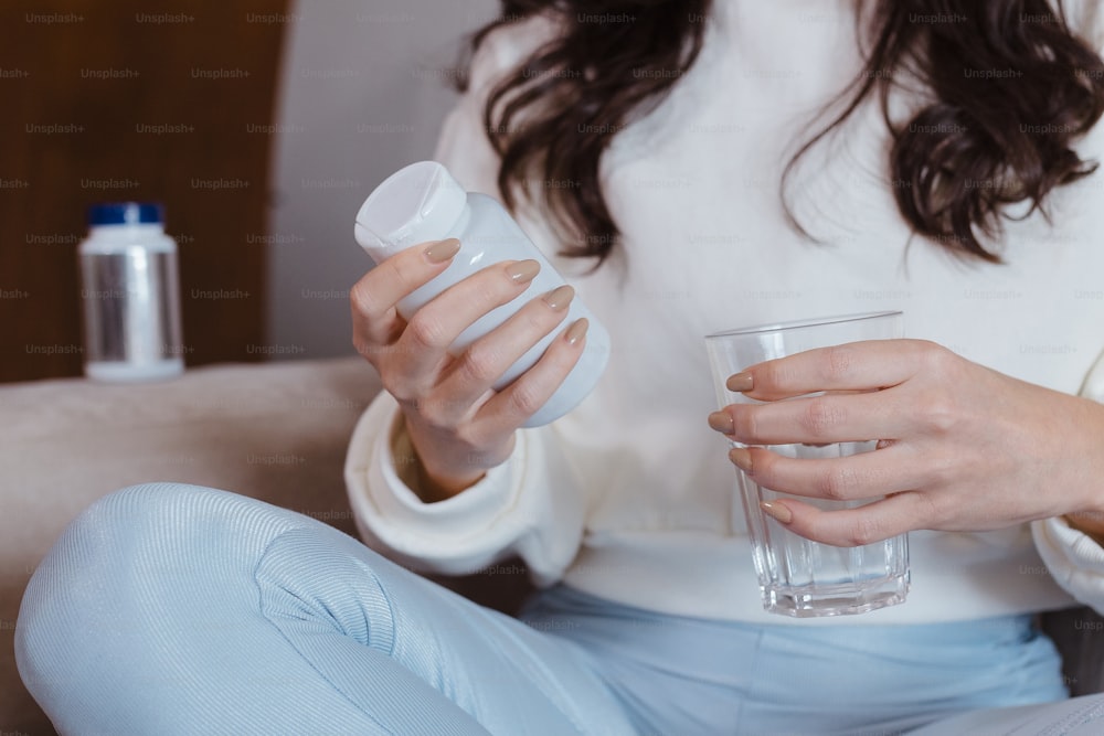 Una mujer sentada en un sofá sosteniendo un vaso de agua