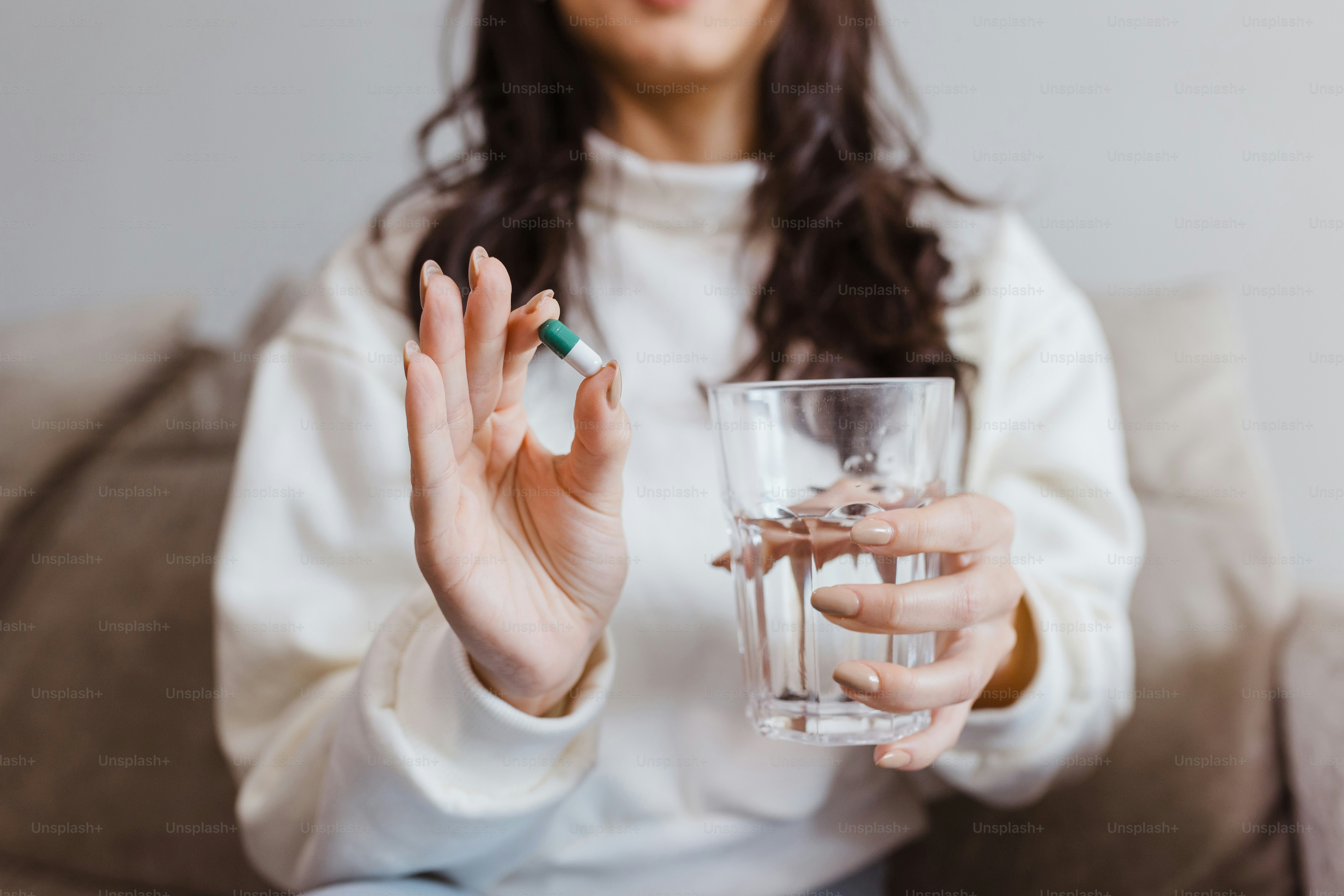 Une femme assise sur un canapé tenant un verre d’eau