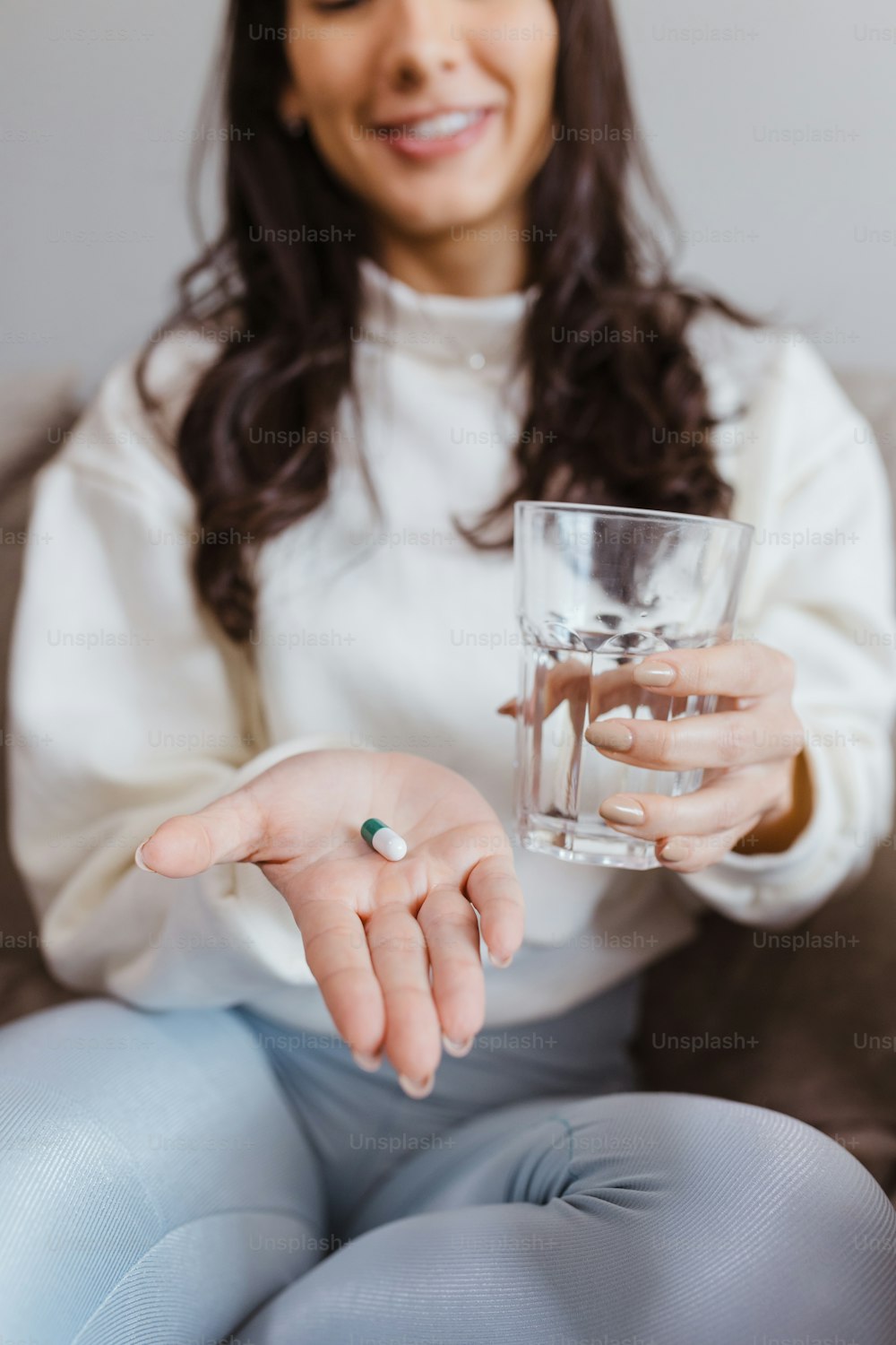 a woman sitting on a couch holding a glass of water