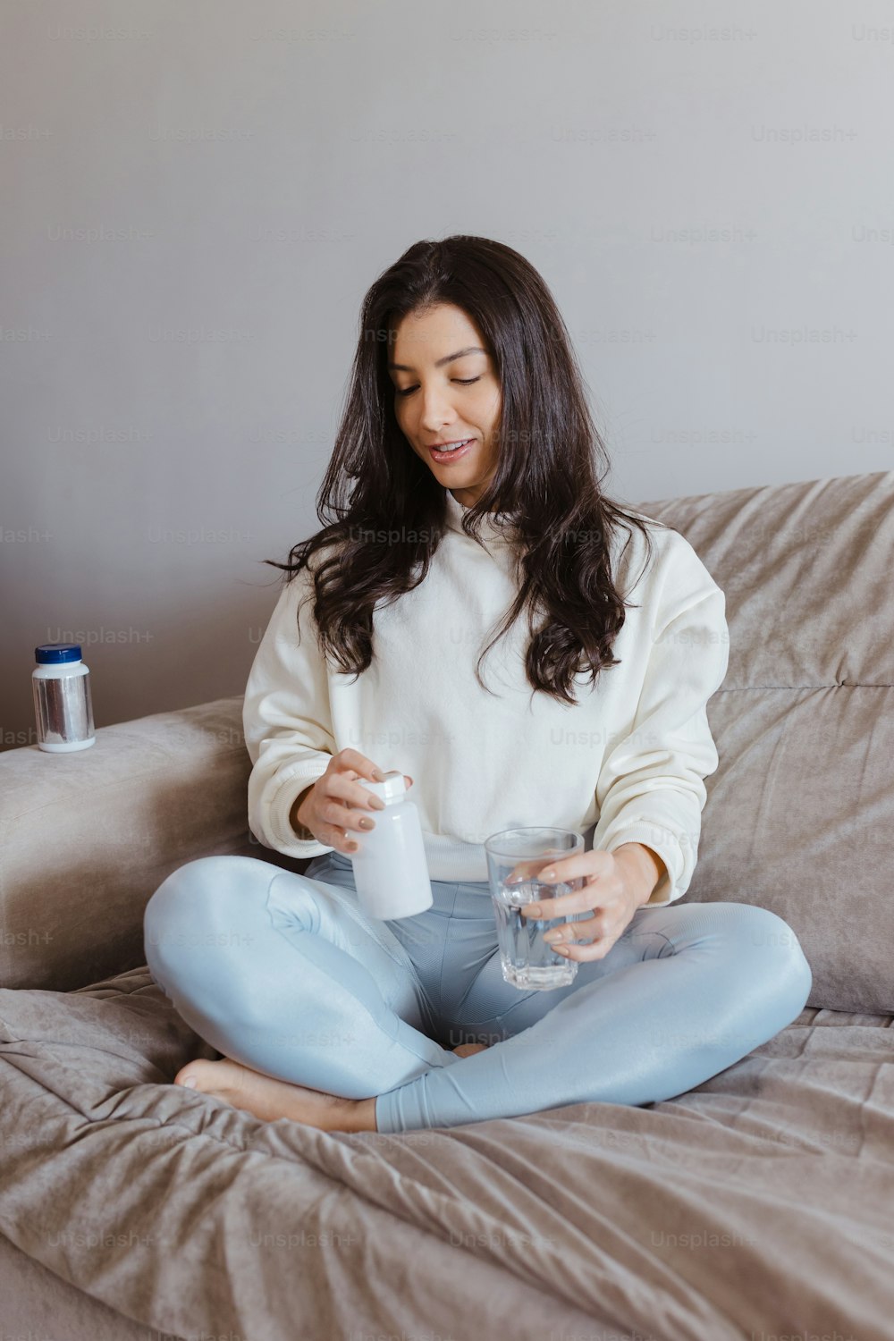 a woman sitting on a couch holding a bottle of water