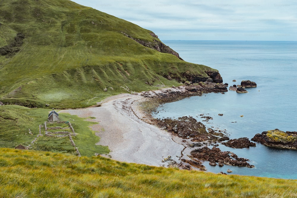 Blick auf einen Strand mit einem grasbewachsenen Hügel im Hintergrund