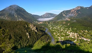 a valley surrounded by mountains with a river running through it